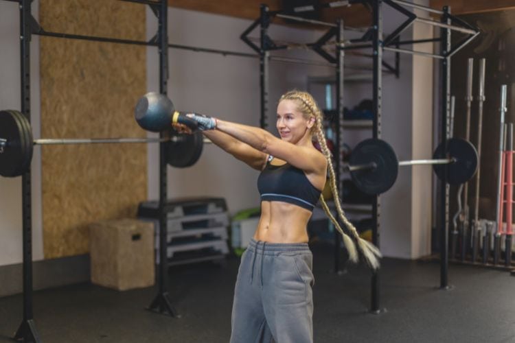 Woman performing a perfect kettlebell swing, demonstrating powerful cardio strength training routine in action.