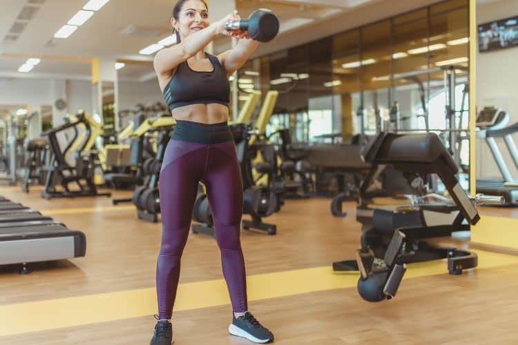 Woman performing a kettlebell swing during a 10 minute full body kettlebell workout at a gym.