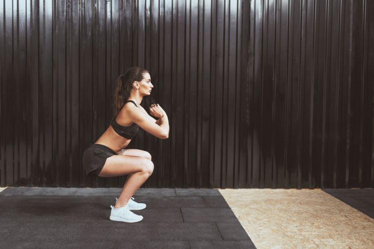 Woman performing a bodyweight superset squat workout at the gym, featuring push-ups and squats during 30 minute bodyweight superset workout.