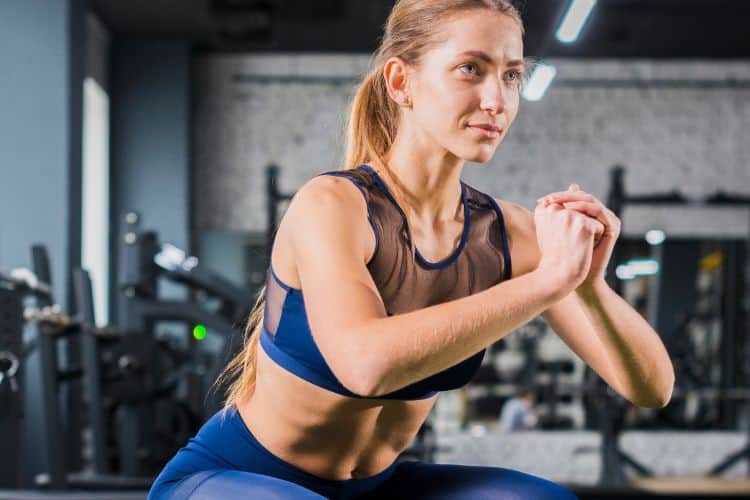 Woman performing a perfect bodyweight squat form for lower body strength in a 2 week bodyweight workout plan.