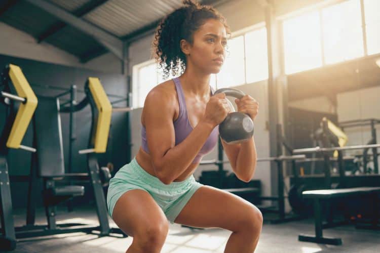 Woman performing a kettlebell goblet squat during a 2 week full-body kettlebell workout plan.