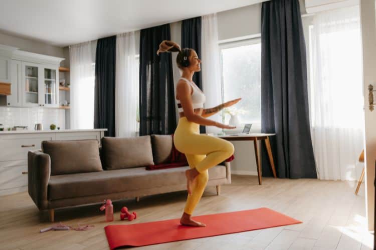 Woman performing high knees in a living room during a 30-minute full body cardio workout at home.