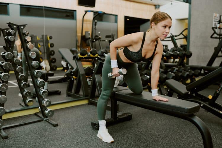 Woman maintaining a flat back while performing a dumbbell row in a beginner full body workout split.