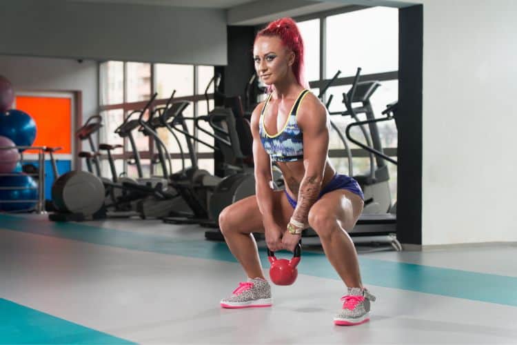 Woman doing early morning kettlebell swing in the gym for best early morning workouts with kettlebell for energy and fat loss.