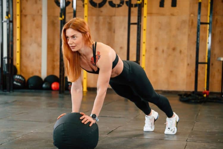 Woman performing push-up in gym during 45 minute morning workout.