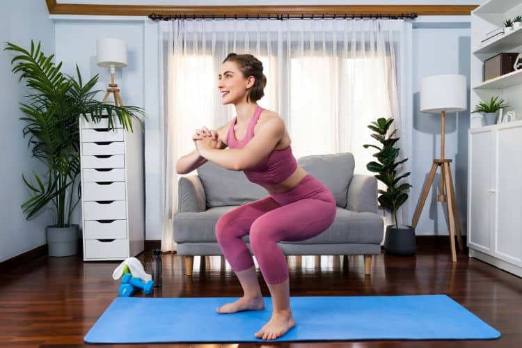 Woman performing bodyweight squat during a 45 minute apartment friendly HIIT workout.