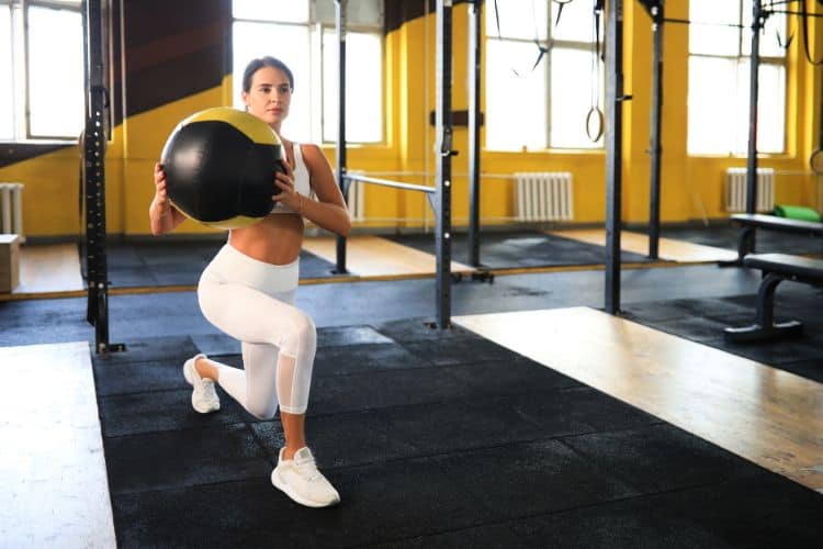 Woman doing easy lunge twist during 45 minute fat burning workout for beginners at a gym.