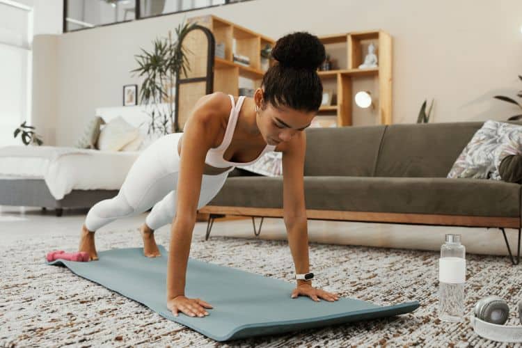 Woman in a living room doing a bodyweight push-up in No equipment 30 minute living room HIIT workout.