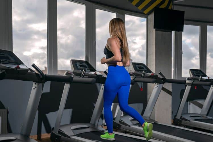 A woman walking on a treadmill set to a 12% incline and 3 mph speed for the viral 12-3-30 workout.