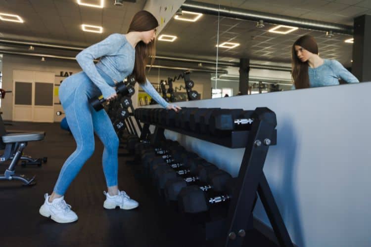 Woman doing a single-arm dumbbell row workout on a bench to correct muscle imbalances and build back strength.