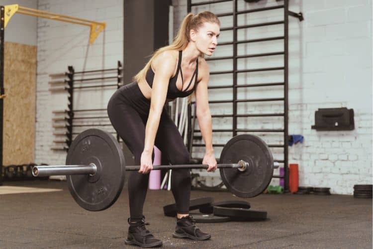 A woman performing a bent-over barbell row workout with correct form, demonstrating a strong, flat back and pulling the barbell towards his lower abdomen.