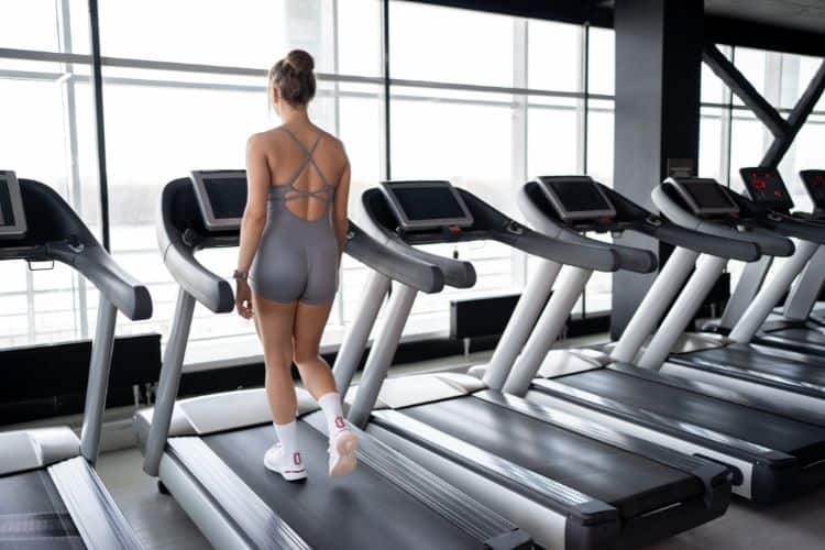 Woman performing the best treadmill incline workout for glutes, walking uphill on a treadmill set to a steep incline.