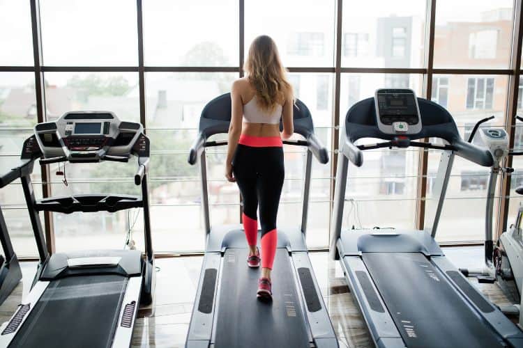Woman running on a treadmill at a high incline, focusing on her 30-minute hill workout to build leg strength and endurance.