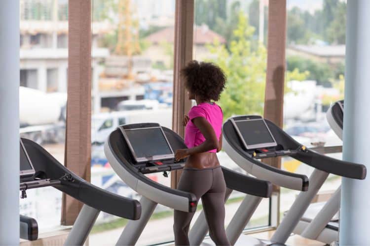 A runner maintains a strong, upright posture and controlled stride during a challenging tempo run workout on a treadmill, exemplifying the comfortably hard effort.