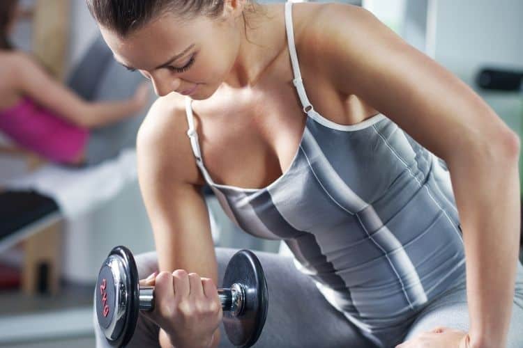 Woman performing a bicep curl as part of a 30 minute dumbbell workout to build strong, toned arms.