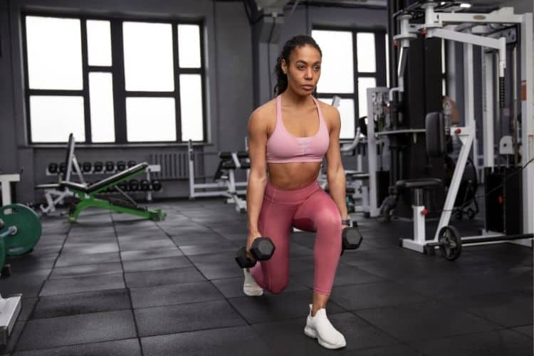 A woman performing a dumbbell reverse lunges during a 10-minute EMOM workout, demonstrating efficient full-body strength training.