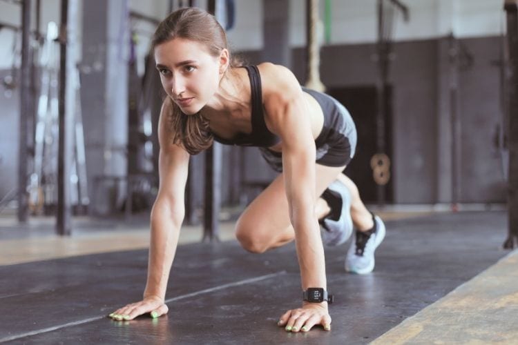 Woman performing a high-intensity mountain climber during a 35-minute HIIT workout for belly fat at the gym.