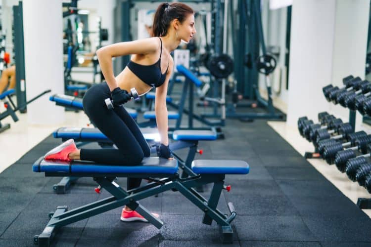 Woman performing bent-over dumbbell row to strengthen back and biceps in 15-minute strength workout.