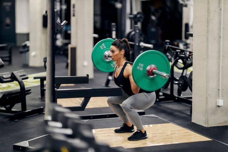 Woman performing barbell squats focusing on lean muscle building during the SplitLean 4-day leg workout routine.