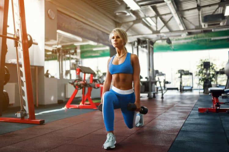 Woman performing a dumbbell lunge as part of the SplitLean 5-Day Strength and Sculpt workout plan.