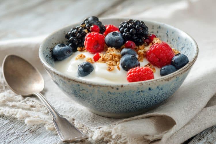 Greek yogurt parfait with mixed berries and granola in a bowl, an energizing breakfast ideas before workout.