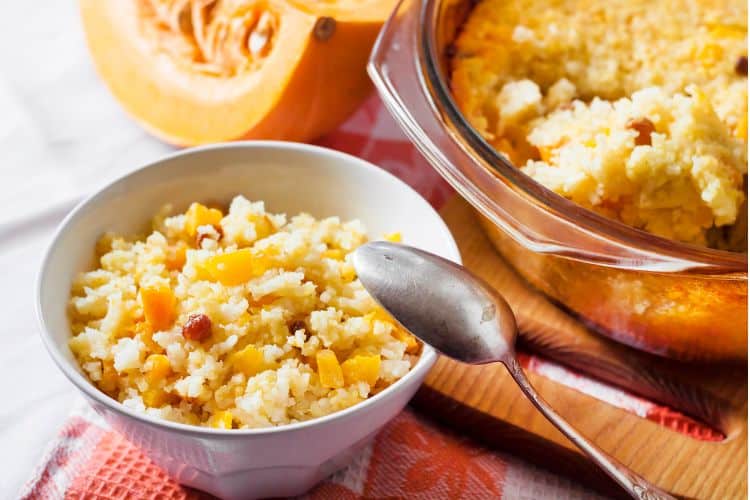 A creamy pumpkin cottage cheese breakfast bowl topped with granola, chopped pecans, and a dusting of cinnamon in a white bowl.