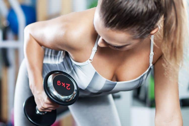 Beginner dumbbell workout plan for women - A confident woman in workout clothes holding dumbbells ready to start her strength training journey.