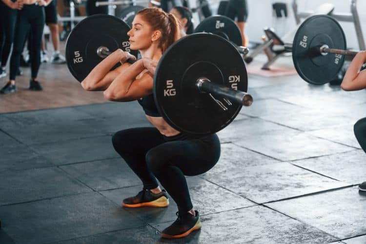A strong woman preparing to lift a heavy barbell in a gym, demonstrating proper strength training form for how heavy women should lift.