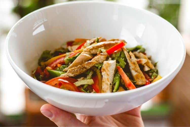 Close-up of a delicious low-calorie homemade meal featuring grilled chicken and roasted bell pepper on a white plate.