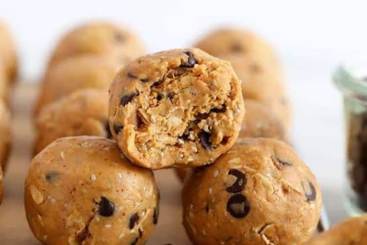 peanut powder protein balls stacked on a white plate with a drizzle of dark chocolate.