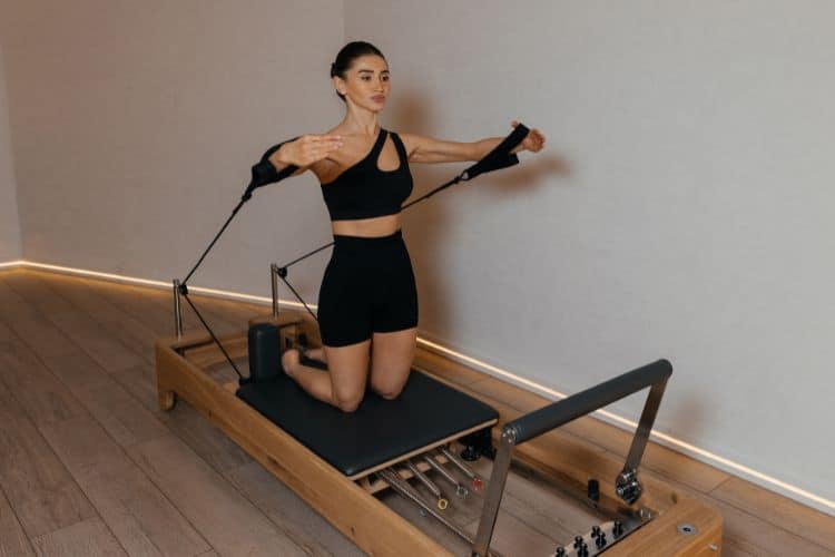 Strong woman over 40 performing a controlled strength workout during a 30 minute strength and Pilates workout.