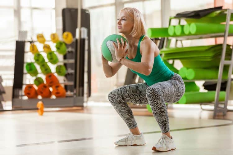 Woman over 50 doing bodyweight squat for a Calisthenics Balance Workout for Women Over 50.
