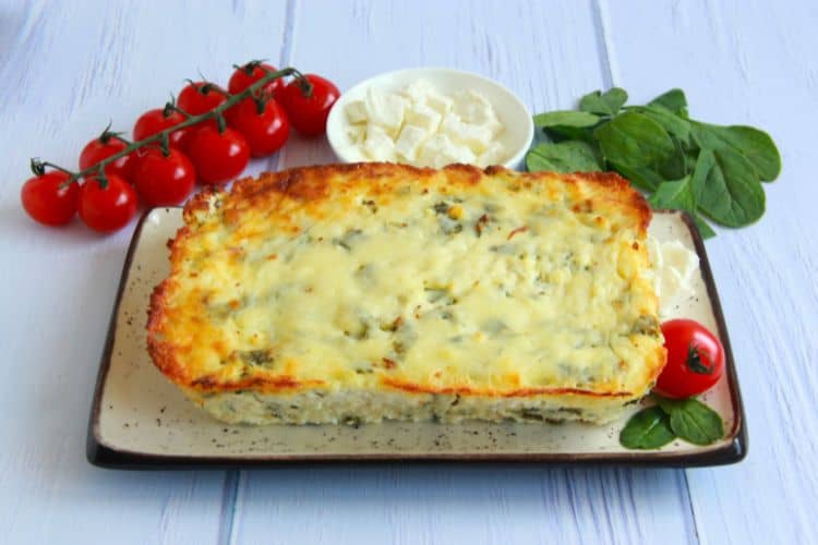 A golden-brown High-Protein Cottage Cheese Breakfast Casserole in a white baking dish, sliced into squares with fresh chives sprinkled on top.