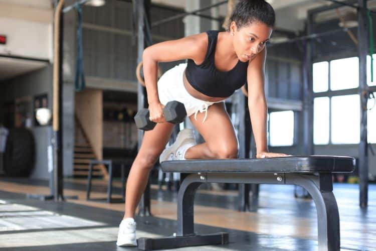 Woman performing dumbbell supersets in a gym for a 2-week full body power workout plan.